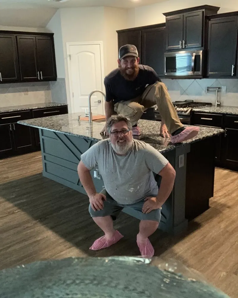 Two Radiant team members posing at a kitchen island in pink shoe covers
