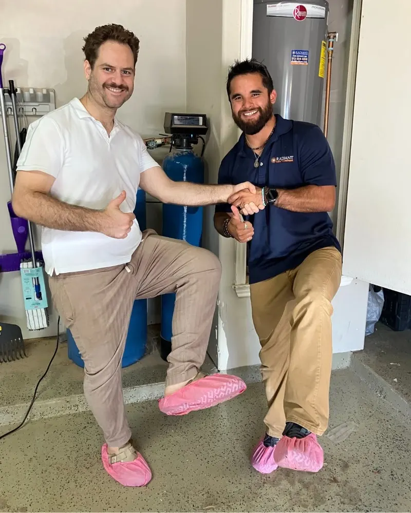 Radiant technician and a customer shaking hands in a garage, both wearing pink shoe covers
