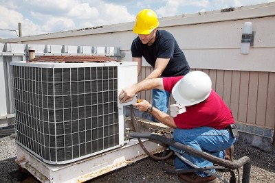 Technicians working on an HVAC unit for a business commercial