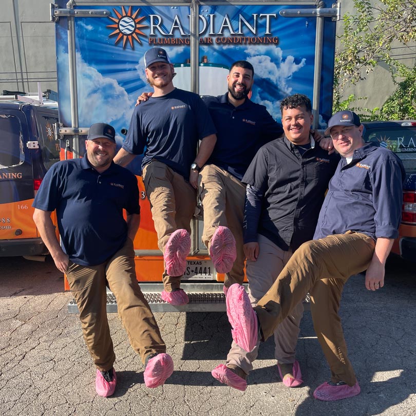 Radiant Technicians standing in front of a work truck in pink booties over their shoes.