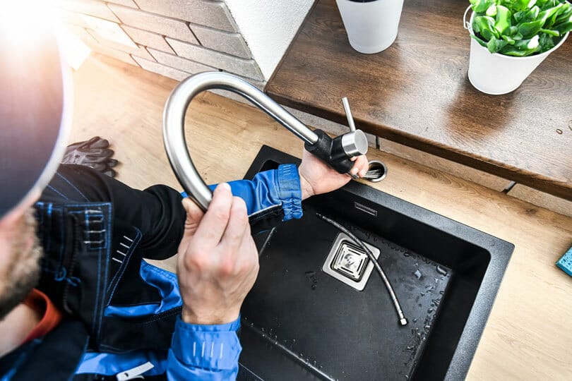 A plumber snaking a kitchen sink drain