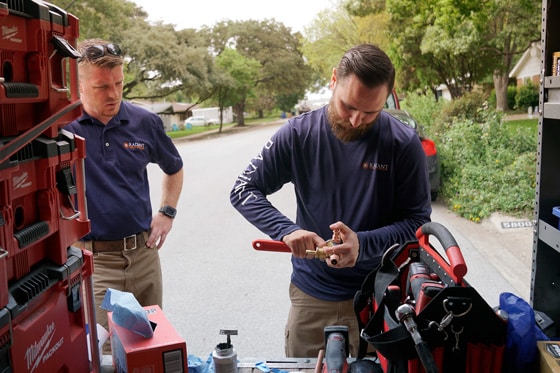 Two Radiant technicians preparing pipes at the back of a truck