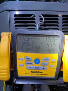 HVAC technician checking refrigerant levels with digital manifold gauge during AC installation