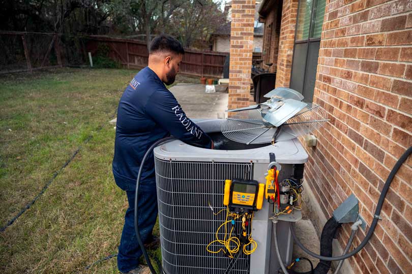 A Radiant HVAC technician performing AC maintenance in San Antonio