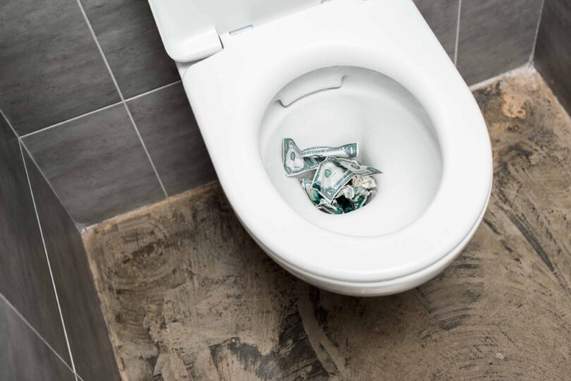 A toilet bowl filled with money to represent the cost of not fixing a constantly running toilet