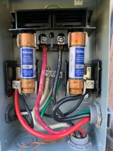 Close-up of an HVAC disconnect box showing dual Edison fuses and connected wiring.