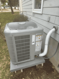 Newly installed heat pump condenser on raised pad next to home in Cedar Park TX