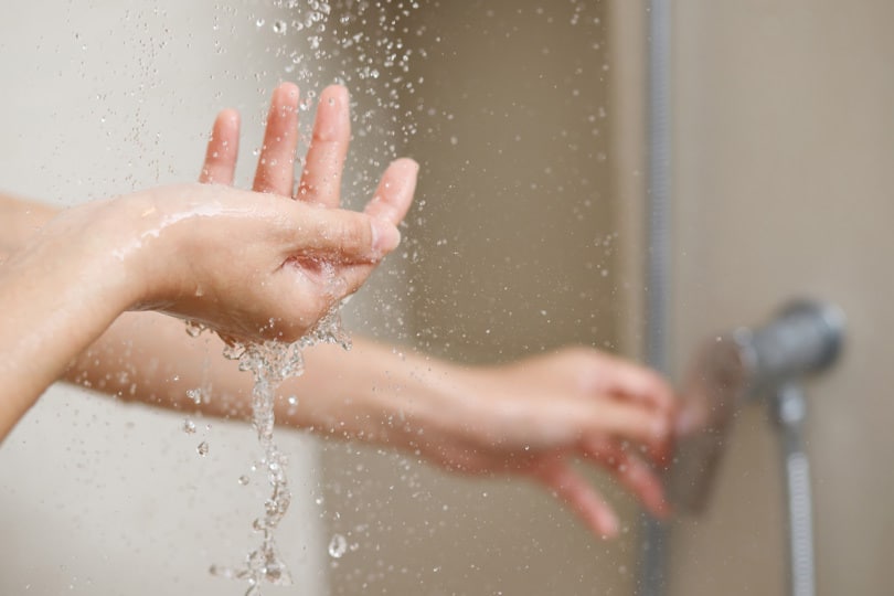 Person's hands adjusting the bathtub shower handle.