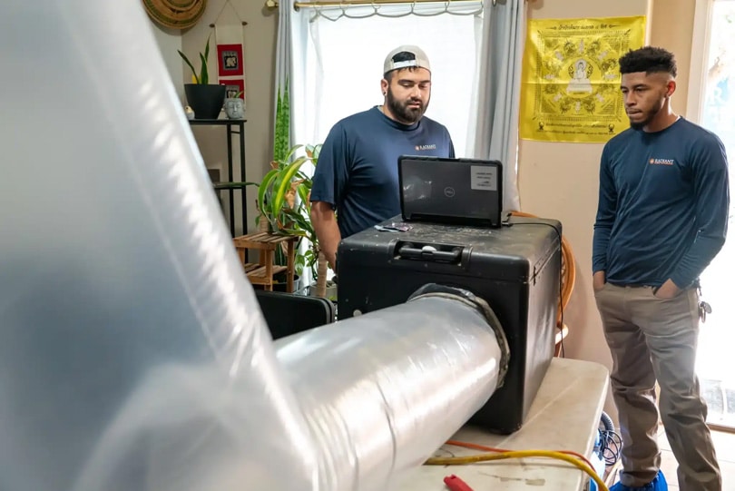 Technicians stand beside an aeroseal testing machines while it works