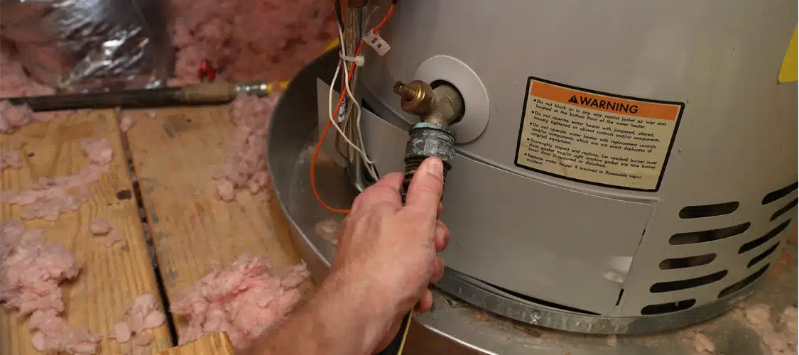 A plumber attaching a hose to drain a water heater located in an attic