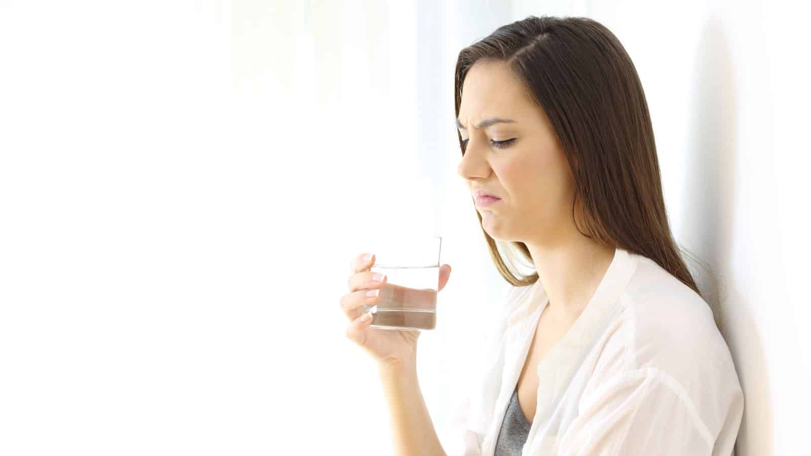 Woman unhappy with the quality of water in her glass